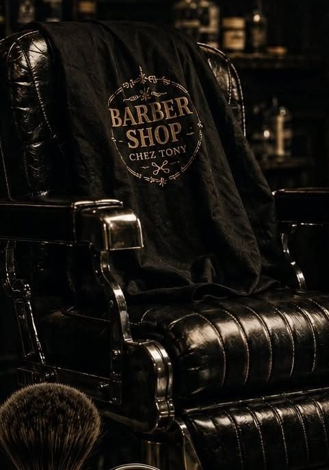 Fauteuil de barbier en cuir noir, cape brodée Barber Shop Chez Tony